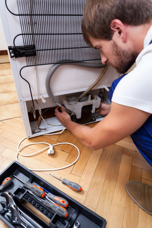 technician repairs the broken fridge